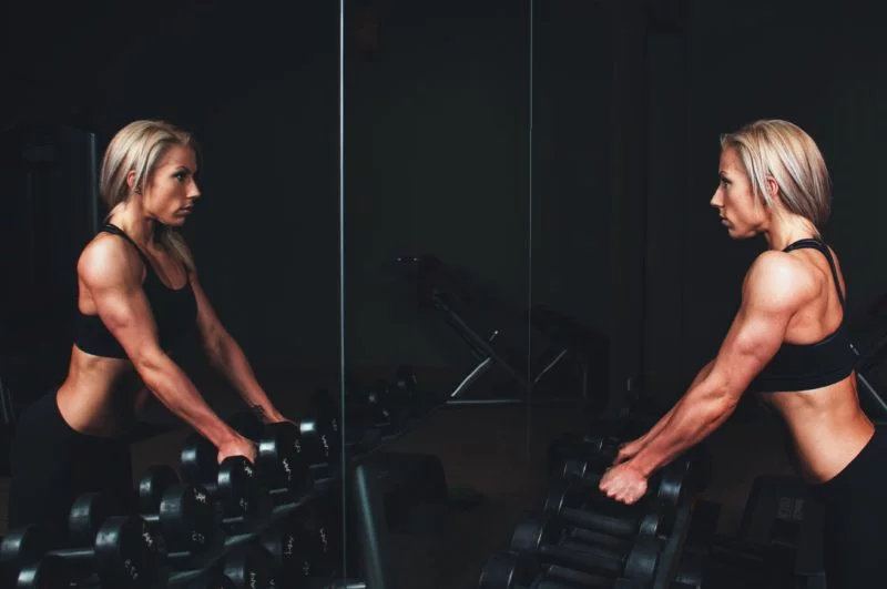 Fitness Model werden | Der ultimative Ratgeber 15 fitness model posiert vor einem spiegel mit hanteln
