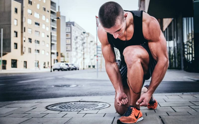 Fitness Model werden | Der ultimative Ratgeber 12 mann bindet sportschuhe auf der strasse