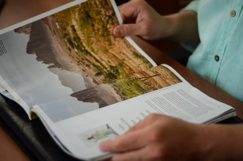 person liest ein magazin mit einem landschaftsfoto