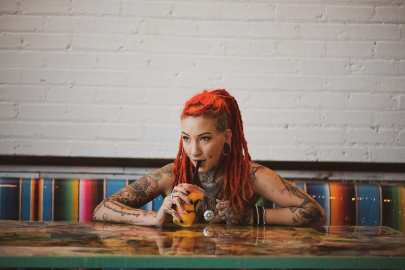 rothaariges tattoo model sitzt am tisch und trinkt