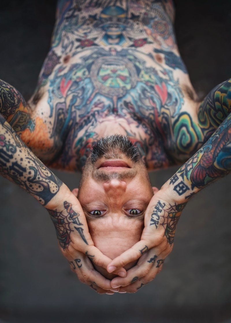mann mit tattoos auf dem Kopf stehend