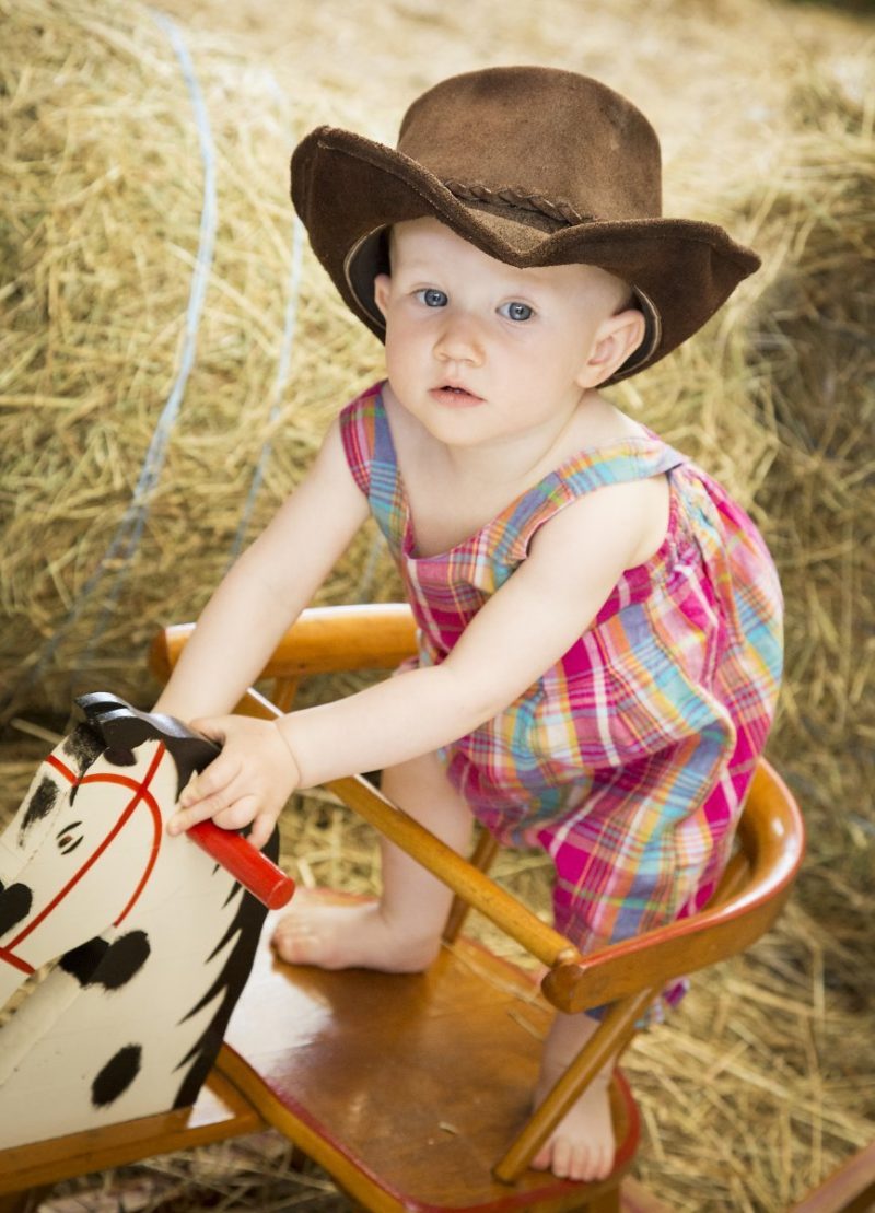 Kinderfotografie von kleinem Jungen mit Cowboy-Hut auf einem Schaukelpferd