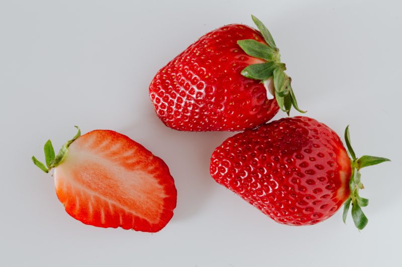 zwei ganze erdbeeren und eine halbe erdbeere in rot