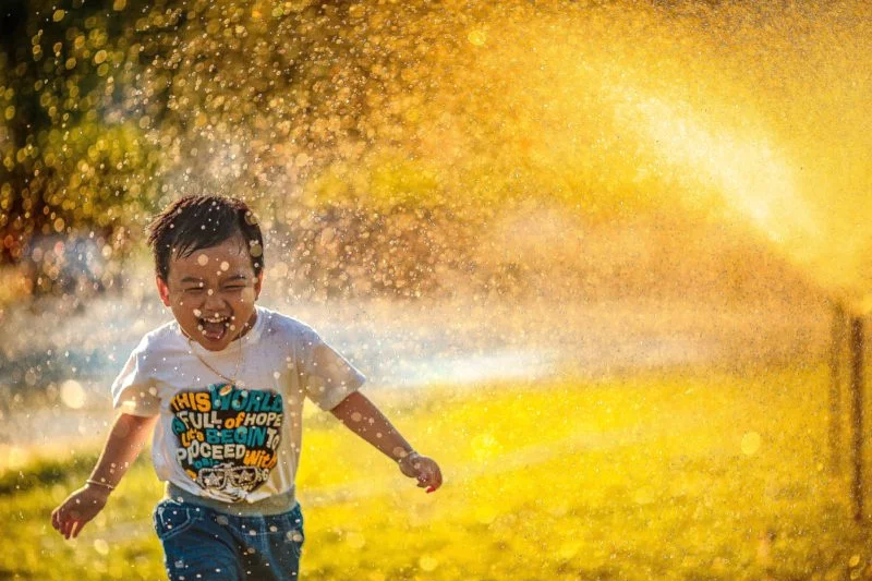 Inszenierte Fotografie vs. spontane Fotografie 12 inszenierte fotografie: kleiner junge rennt durch sprinkleranlage