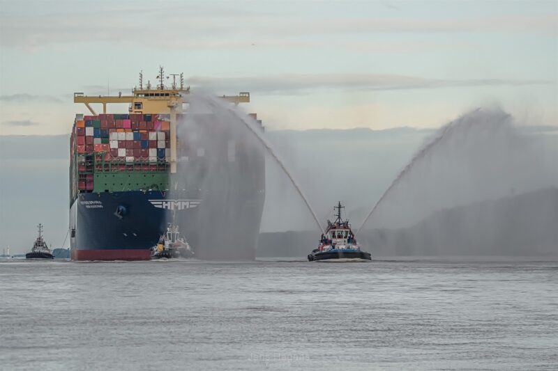 schiffsfotografie eines containerschiffs wird von schlepper in den hafen gezogen