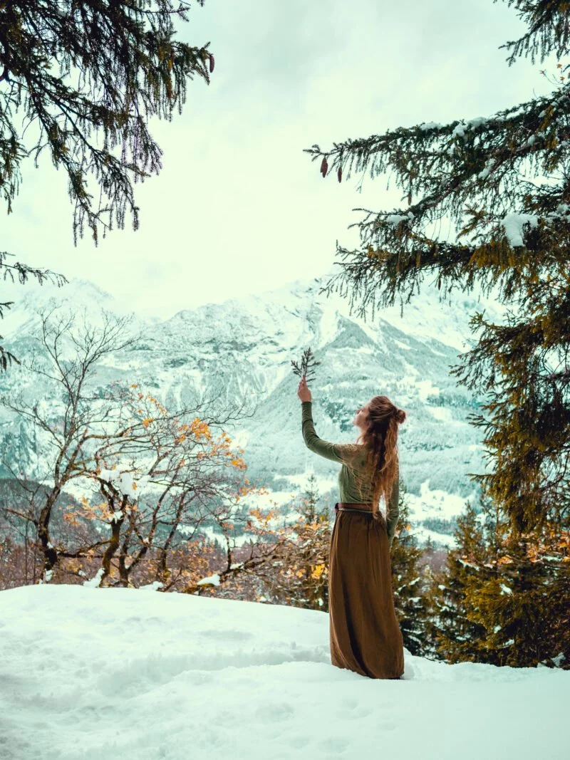 frau haelt zweig in die luft in winterlandschaft