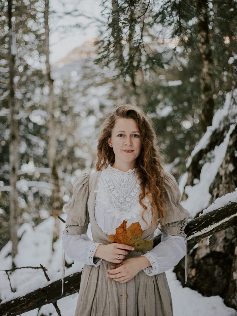 selbstportraits in winterlandschaft mit kleid und blaetter in der hand