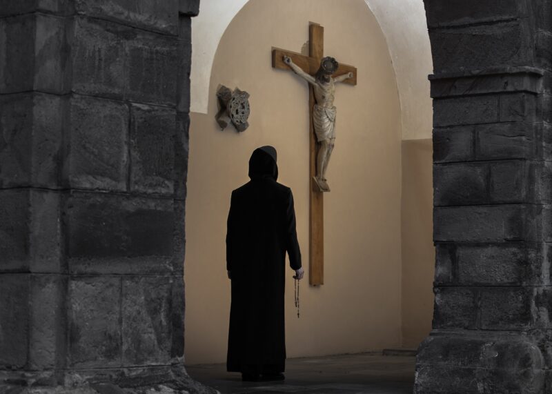 heimatfotografie von moench der in die kirche mit kreuz in der hand laeuft