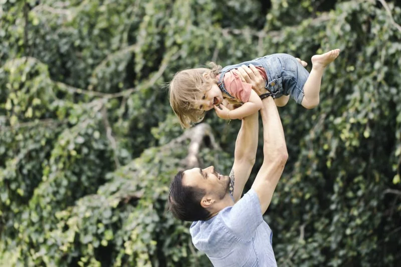 outdoorshooting mit kinder wobei vater seine tochter in die luft hebt